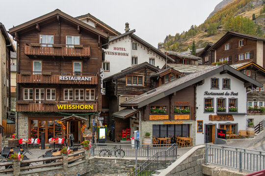 ZERMATT, SWITZERLAND - OCTOBER 20, 2025: Restaurants and Hotels in Autumn on Cloudy Day in Town Center. Zermatt, Valais, Switzerland