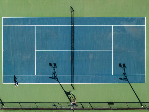 Aerial view of a tennis court with the long shadows of the court lights stretching across the green and blue surface, Thimphu, Bhutan.