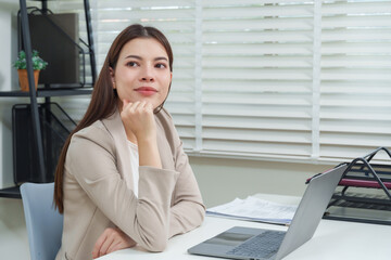 Asian woman professional worker thinking and smiling during online meeting at office representing teamwork communication business consultation corporate digital telework cooperation technology concept