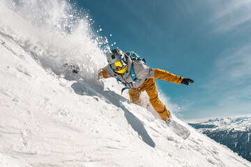 Fototapeta premium Fast man snowboarder rides in cloud of powder snow outside ski slope. Backcountry or offpiste free riding at ski resort