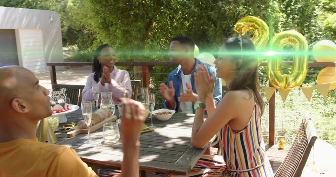 Four friends clapping after blue-shirt speaking birthday, gold 30, green flare hiding faces, events