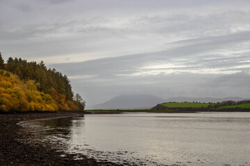 A tranquil autumn landscape near the sea at low tide with a view of the mountains