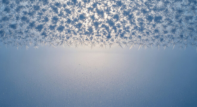 Close-up of ice crystals on glass, creating a complex, fractal pattern. Represents winter, cold, and the beauty of natural formations, free space below