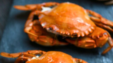 Two deliciously cooked whole crabs on a dark surface
