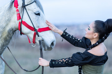 Charming European lady posing with a majestic white horse in an open field, symbolizing freedom, calmness, and connection with nature.