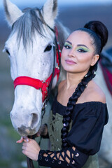 Charming European lady posing with a majestic white horse in an open field, symbolizing freedom, calmness, and connection with nature.