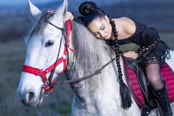 Charming European lady posing with a majestic white horse in an open field, symbolizing freedom, calmness, and connection with nature.