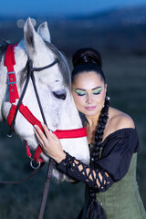 Charming European lady posing with a majestic white horse in an open field, symbolizing freedom, calmness, and connection with nature.