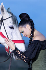 Charming European lady posing with a majestic white horse in an open field, symbolizing freedom, calmness, and connection with nature.