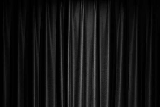 Black Background.   Close-up of elegant Black stage curtains with soft folds and warm lighting, creating a dramatic and textured backdrop for theater or performance.	