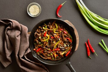 Fried thinly sliced beef steak with peppers in cast iron skillet