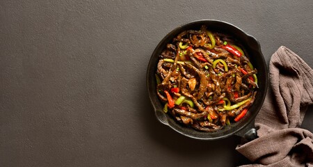 Fried thinly sliced beef steak with peppers in cast iron skillet