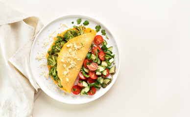 Omelet with roasted broccoli and cheese served with salad from fresh vegetables