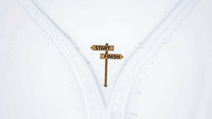 Signpost labeled Start and Finish on snowy trail with running tracks  