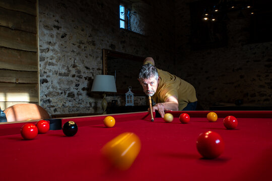 A game of pool with a pool player taking a shot. Motion blur on the yellow ball heading towards camera. 