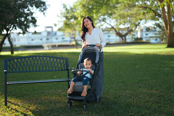 Fototapeta premium Asian mother pushing baby in stroller in park