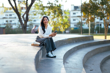 Young woman relaxing on park steps using smartphone