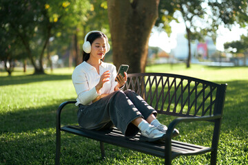 Woman relaxing in park enjoying music with headphones
