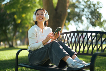 Young woman enjoying music streaming on smartphone in a park