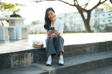 Young woman smiling using smartphone in park