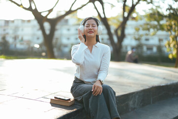 Young woman enjoying music with headphones relaxing outdoors