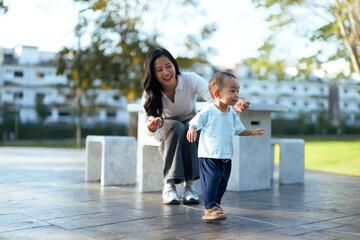 Toddler learning walking with mother in park