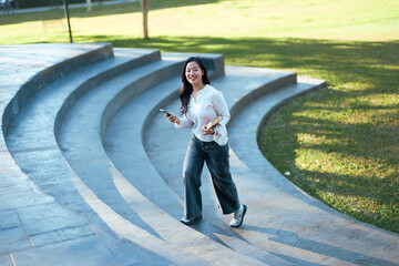 Happy student walking up outdoor stairs using phone