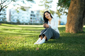 Young woman enjoying coffee relaxing in park grass