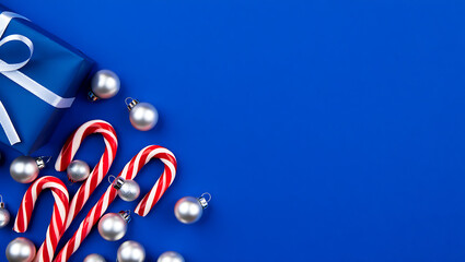 A festive Christmas background with a corner border of silver candy canes and blue ornaments on a blue surface.