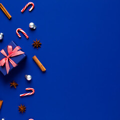 A festive Christmas background with a corner border of blue gifts, candy canes, and spices on a blue surface.