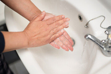 A woman washes her hands thoroughly with soap after using a toilet. A woman always takes care of personal hygiene