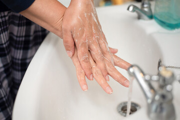 Close-up of hands being washed with soap under running water at a bathroom sink. Highlights personal hygiene, cleanliness, and daily care. Perfect for health, wellness, and cleanliness