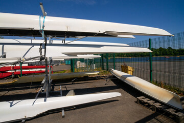 Rowing boats stored on outdoor racking systems at Watersports Centre at Strathclyde Country Park Scotland. UK. The boats are long, narrow, and lightweight vessels for the sport of competitive rowing. 