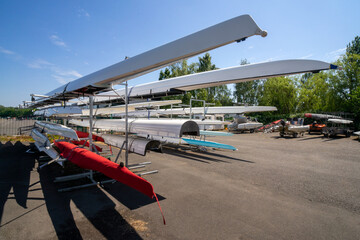 Rowing boats stored on outdoor racking systems at Watersports Centre at Strathclyde Country Park Scotland. UK. The boats are long, narrow, and lightweight vessels for the sport of competitive rowing. 