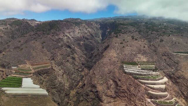 Expansive aerial view of rugged mountainsides featuring ancient terraced agriculture on La Palma, Canary Islands.