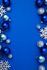 A modern Christmas background with a vertical side border of blue and silver ornaments and snowflakes on a blue surface.