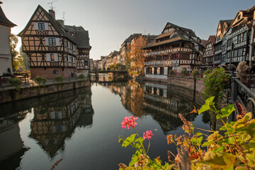 Naklejka premium Half-timbered houses of Petite France in Strasbourg line river at sunset