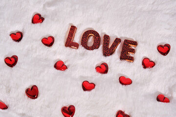 The inscription is LOVE on a white plush background with hearts. Background.