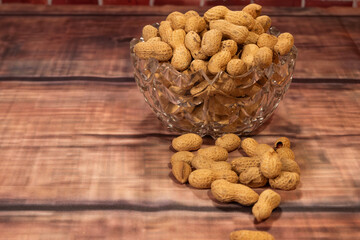 Peanuts in their shells spilled from a vase onto a table