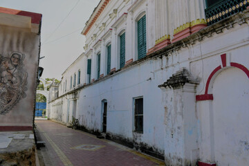 a quiet heritage lane at nasipur akhra with old white walls, green shutters and a painted mural adding character to the historic passage at murshidabad