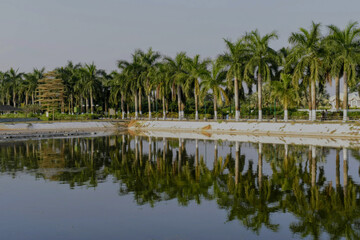 Obraz premium a calm waterbody in motizheel park with palm trees, soft greenery and glowing reflections creating a peaceful light and sound show atmosphere