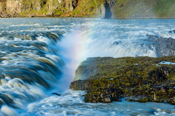 Morning light creates a magical rainbow in the powerful churning flow of a big river in Iceland