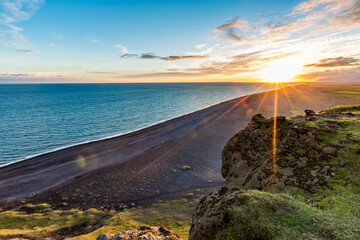 Stunningly beautiful sunset over the ocean as seen from the cape cliffs near the lighthouse of Vik, small city in Southern Iceland, travel tourist destination and sightseeing