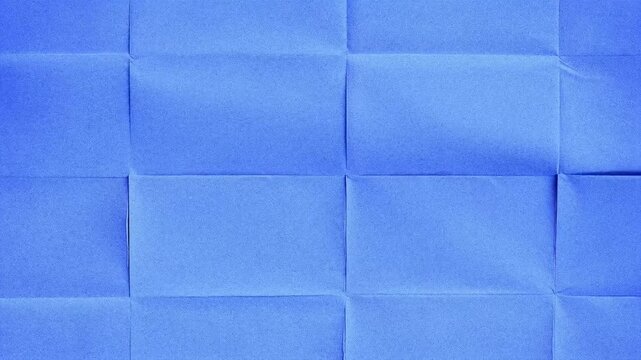 Close-up of blue textured paper with visible creases and folds creating a geometric pattern.