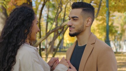 Hispanic happy couple talking communicating carefree in autumn park multiethnic family Caucasian woman talk conversation speaking with Arabian man in autumnal city sharing funny news laughing smiling