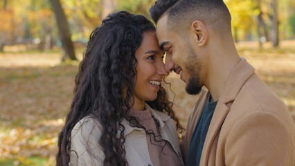 Close up smiling Hispanic couple touching foreheads faces kissing noses smile Arabian man Caucasian woman multiethnic people in love family dating in autumn fall park city relationship partners happy