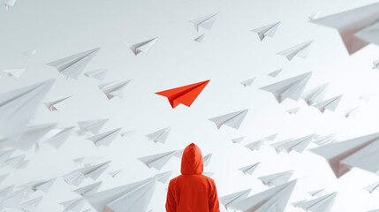 Person surrounded by paper airplanes with a red airplane standing out, concept of individuality and focus
