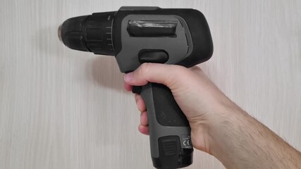 Still shot of a cordless power drill standing upright on a workbench shown from a side profile perspective highlighting the ergonomic design