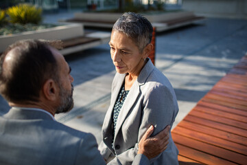 Mature coworkers in a serious, comforting talk in office courtyard