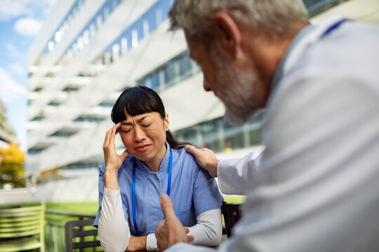 Adult nurse stressed as senior doctor comforts her outside hospital - Powered by Adobe